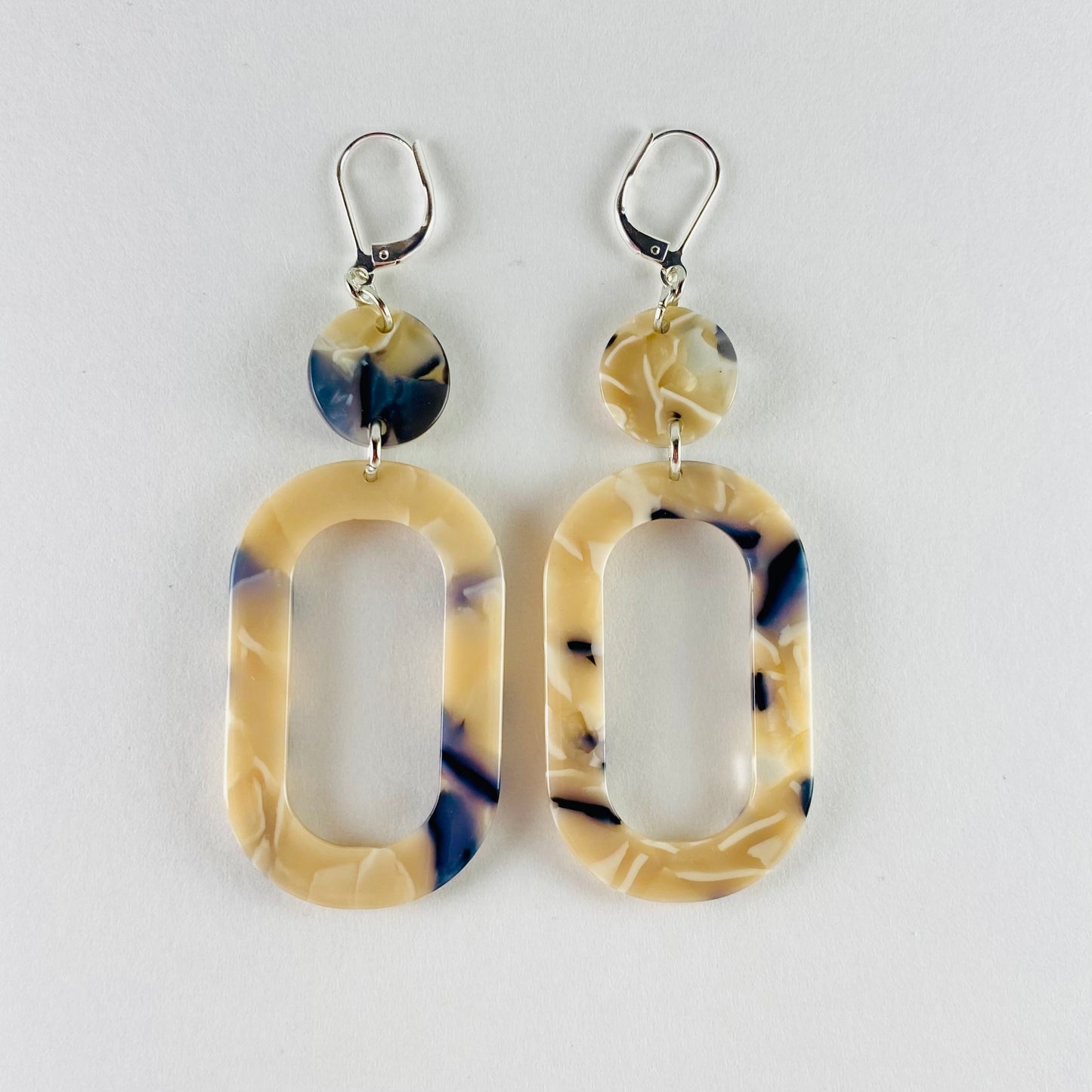Dangling earring with 2 geometric shaped beads, both marble-colored with beige, midnight blue and white.