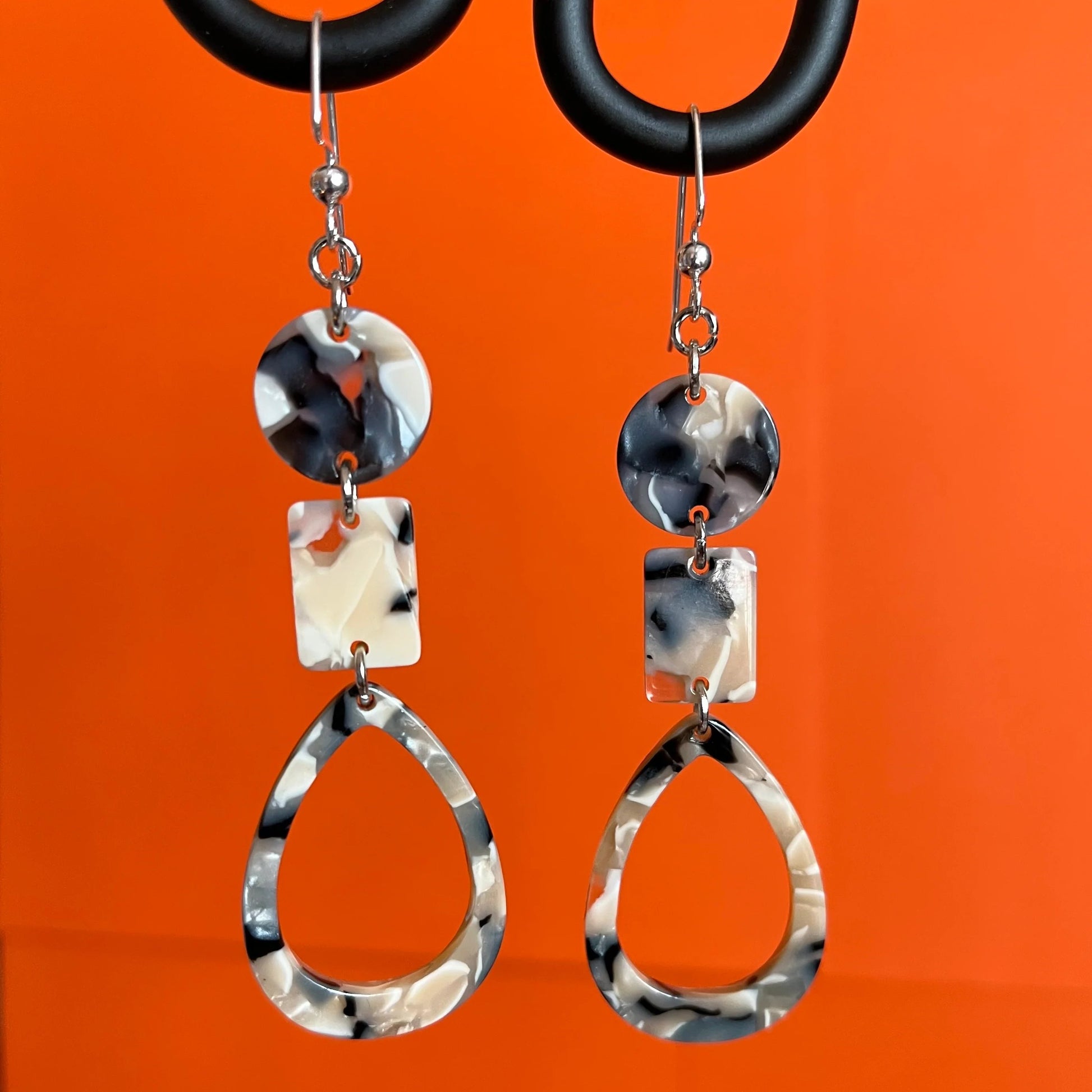 Dangling earring with 3 geometric beads. All beads are marbled:  midnigh blue, beige and white. One disc, one rectangle and one teardrop donut.