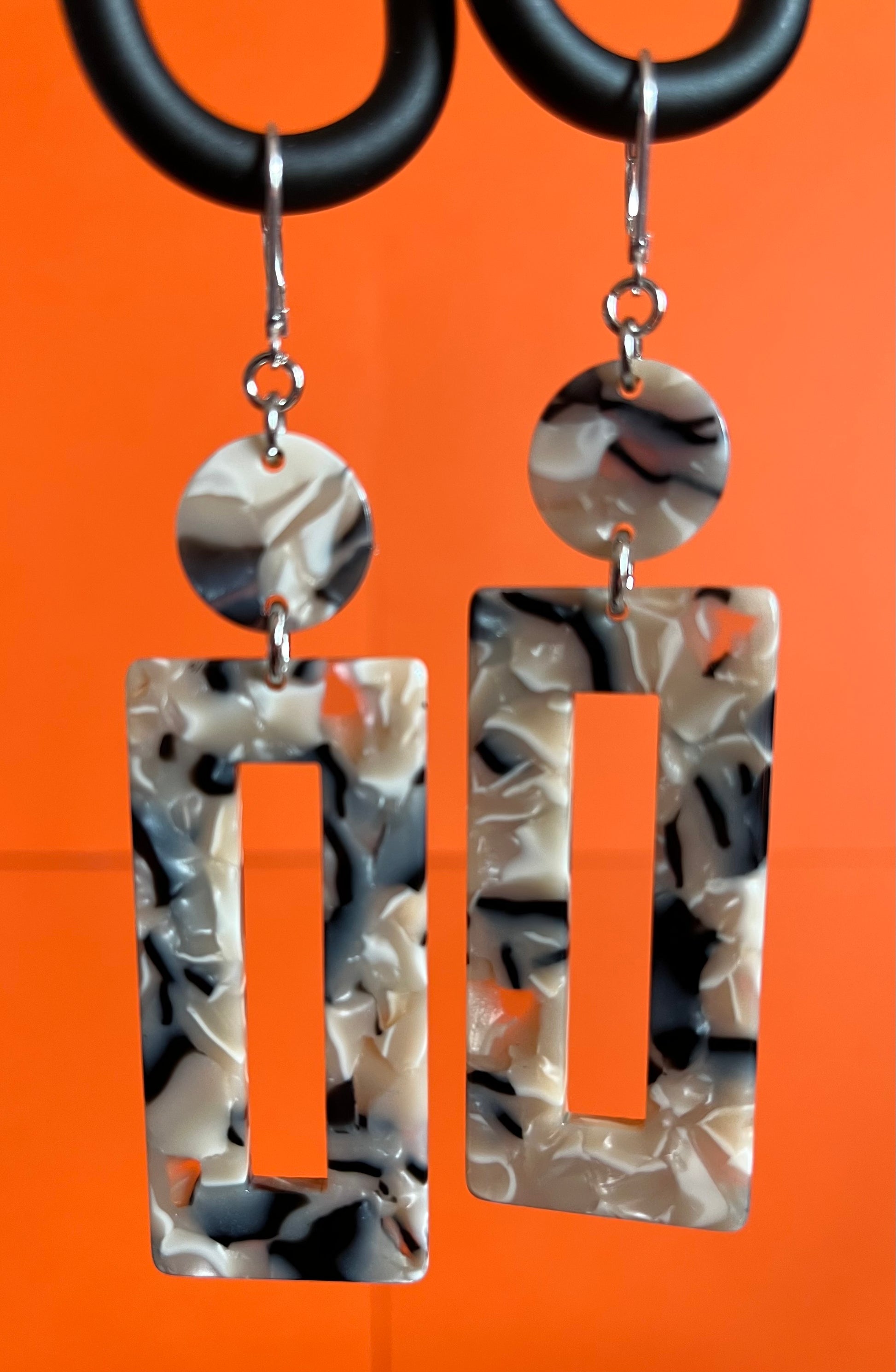 Dangling earring with two geometric shaped beads. One dime shaped and one donut shaped rectangle.  Marbled beige, midnight blue and white.