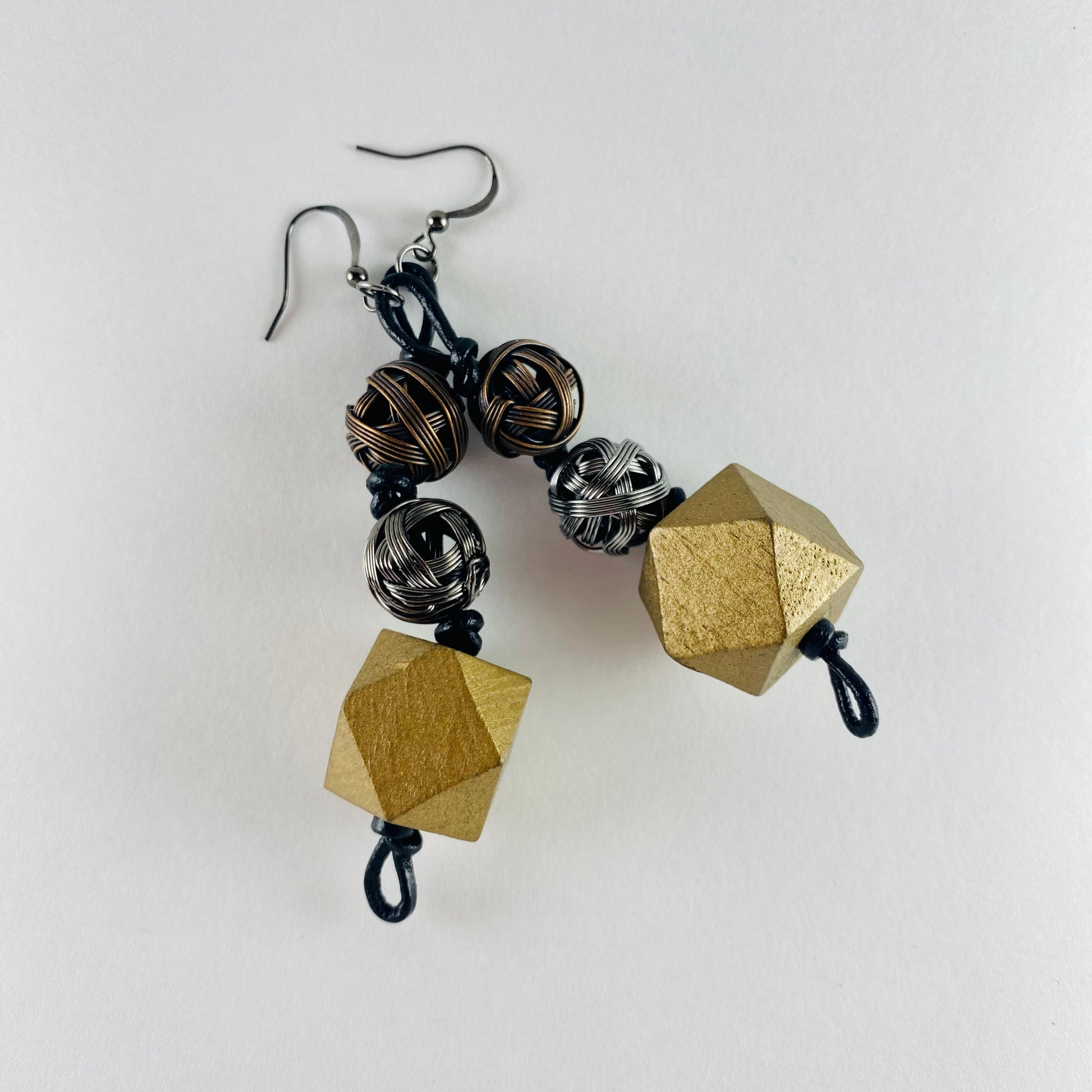 Dangling earring with 3 geometric beads. One multifaceted shaped wood bead and two metal wire spheres. One silver and one bronze.
