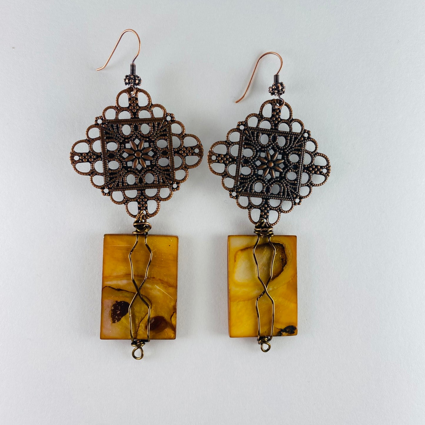 Dangling earrings 2 components.  One filigree focal and one flate amber rectangle glass bead.