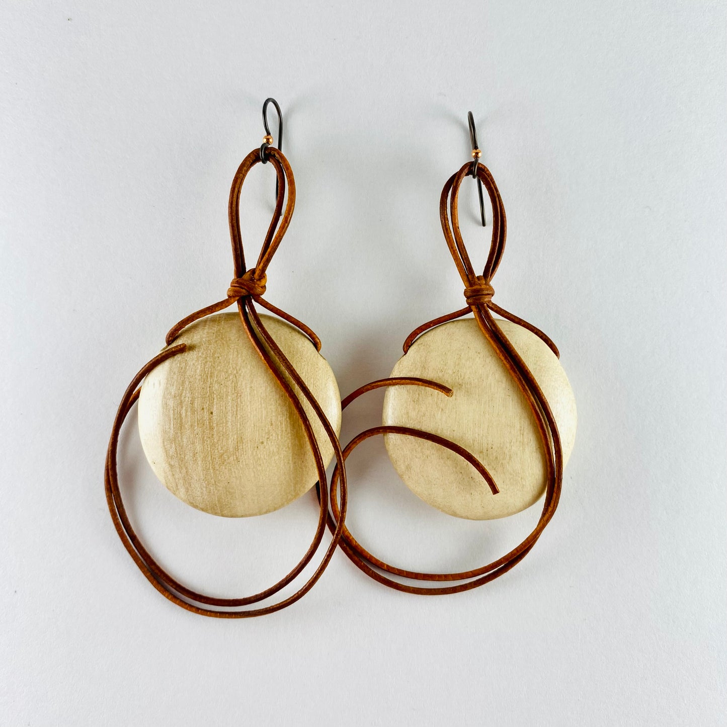 Dangling earring with blond wooden disk attached with 1mm leather cord 