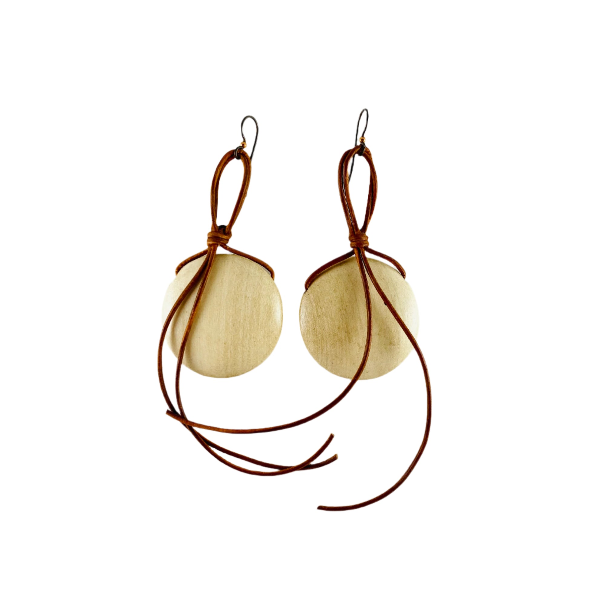 Dangling earring with blond wooden disk attached with copper colored leather cord.