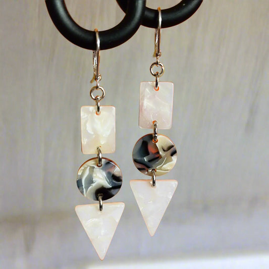Dangling earring with 3 geometric shaped beads.  Two pearlish white and one midnight blue.