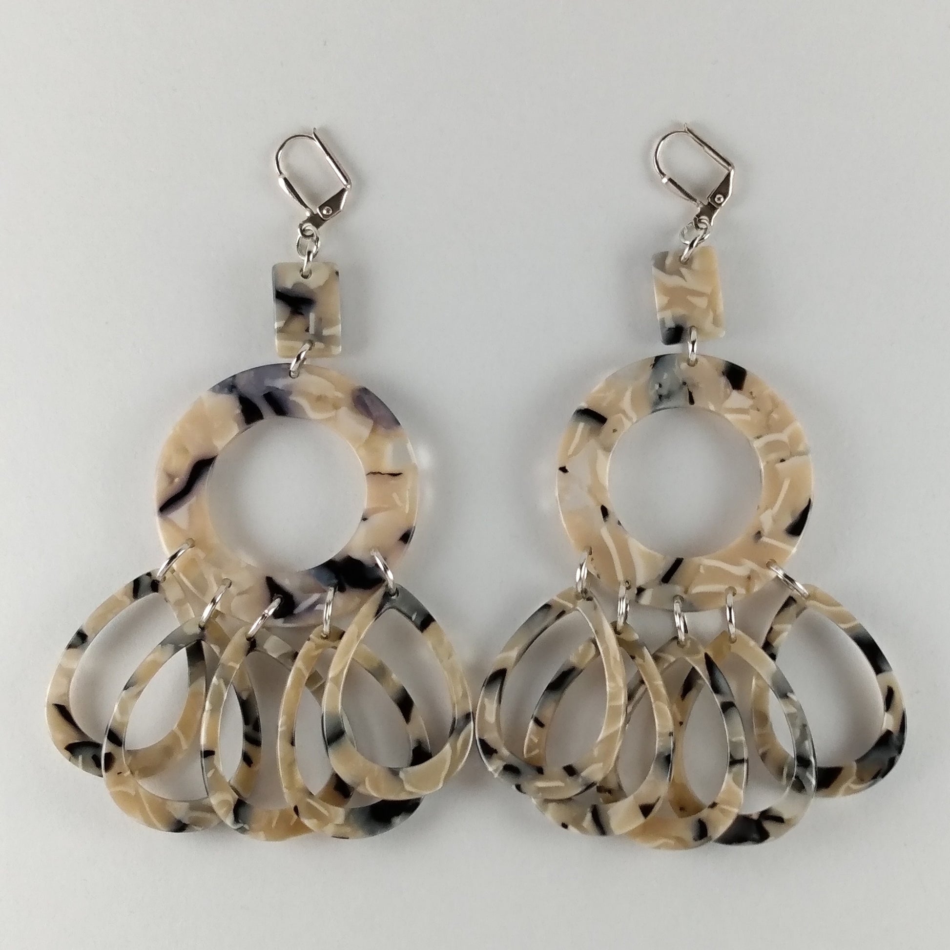 Chandelier earrings with 3 marbled midnight blue beads.  A small rectangle, connected to a round donut with five individual teardrop beads.