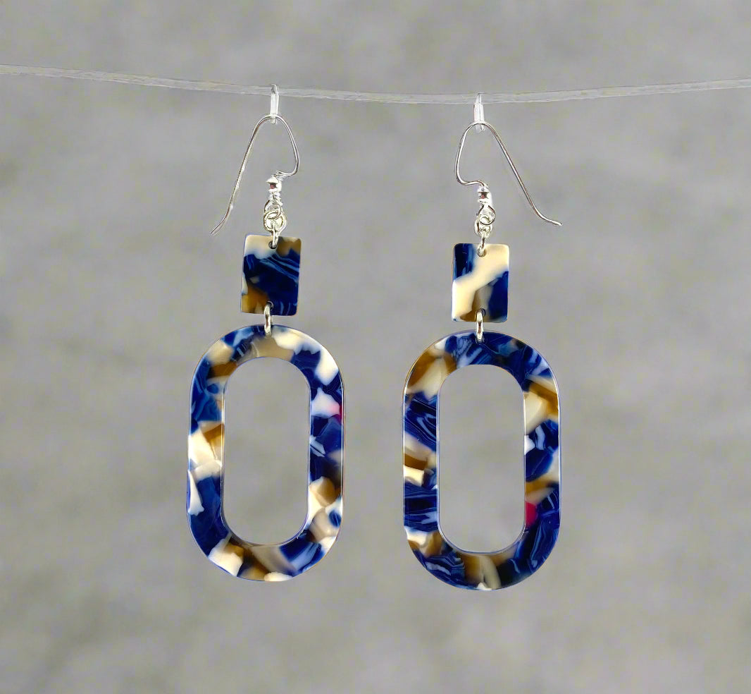 Dangling earrings with 2 geometric shaped beads in marbled blue with other colors.  A small rectangle bead and an oval shaped donut bead.