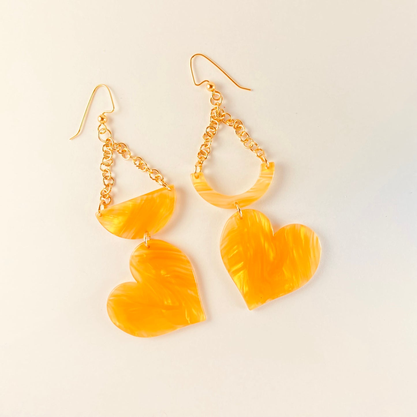 Dangling earring made of acetate with a crescent and half moon shaped beads combined with a heart shaped bead and attached with gold chain.